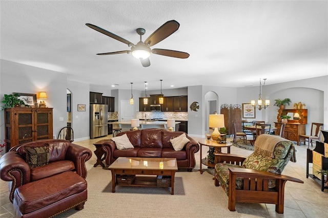 living room featuring a textured ceiling, ceiling fan with notable chandelier, and light tile patterned flooring