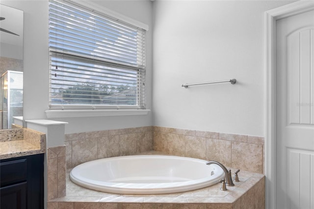 bathroom with vanity and tiled tub