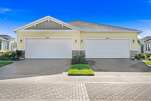 view of front facade featuring an attached garage, stone siding, decorative driveway, and stucco siding