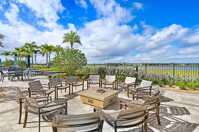 view of patio featuring a fire pit, a water view, and fence