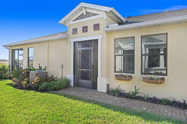 entrance to property with a yard and stucco siding