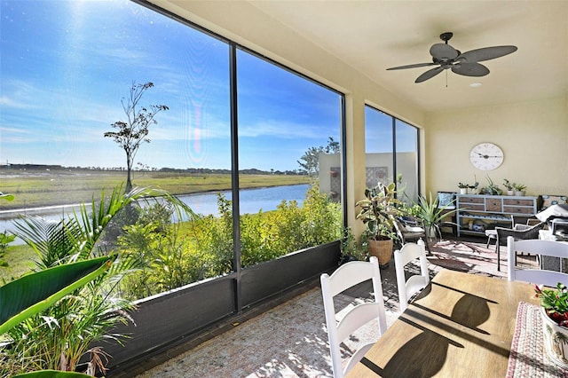 sunroom featuring a water view and ceiling fan