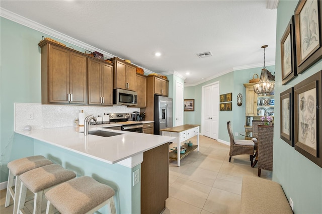 kitchen featuring stainless steel appliances, visible vents, light countertops, hanging light fixtures, and a peninsula