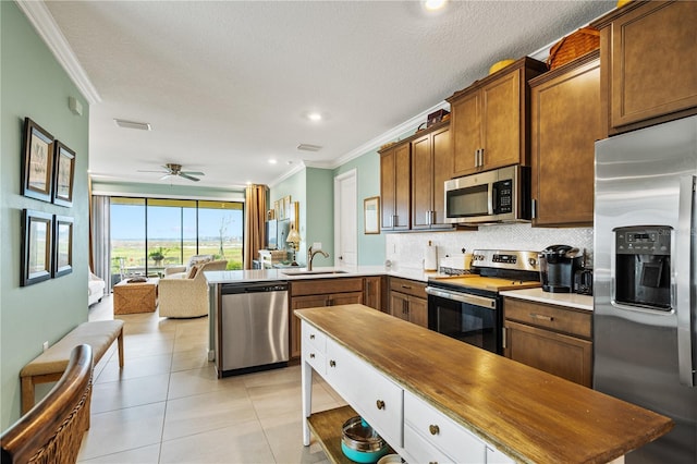 kitchen featuring appliances with stainless steel finishes, crown molding, a sink, and decorative backsplash