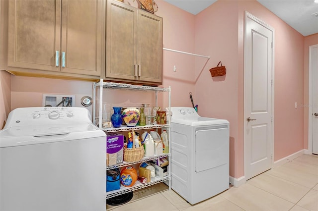 washroom featuring cabinet space, washing machine and dryer, light tile patterned floors, and baseboards