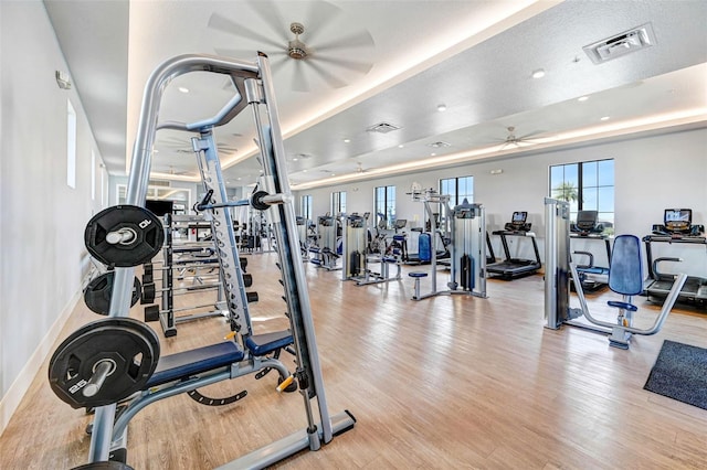 workout area with ceiling fan, light wood-type flooring, visible vents, and baseboards