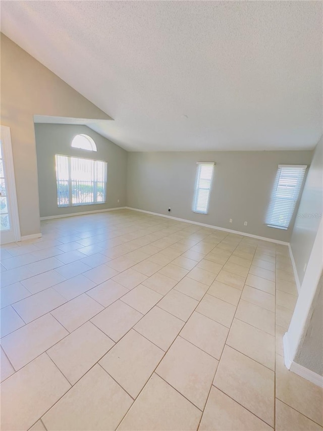 tiled spare room with a textured ceiling and vaulted ceiling