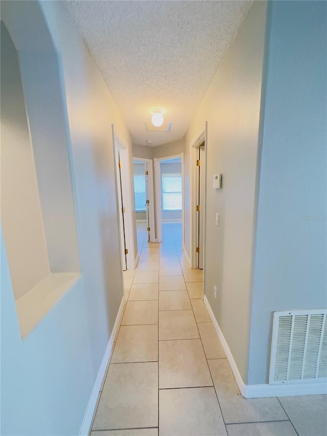 hall with light tile patterned floors and a textured ceiling