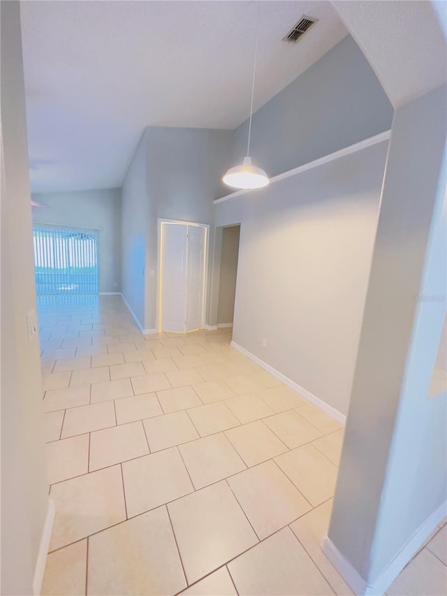 empty room with light tile patterned floors, vaulted ceiling, and ceiling fan