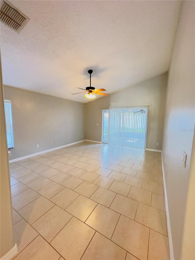 spare room with a textured ceiling, ceiling fan, lofted ceiling, and light tile patterned flooring