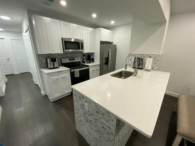 kitchen featuring sink, backsplash, kitchen peninsula, white cabinets, and appliances with stainless steel finishes