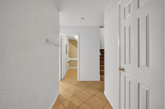 hall featuring light tile patterned flooring and a textured ceiling