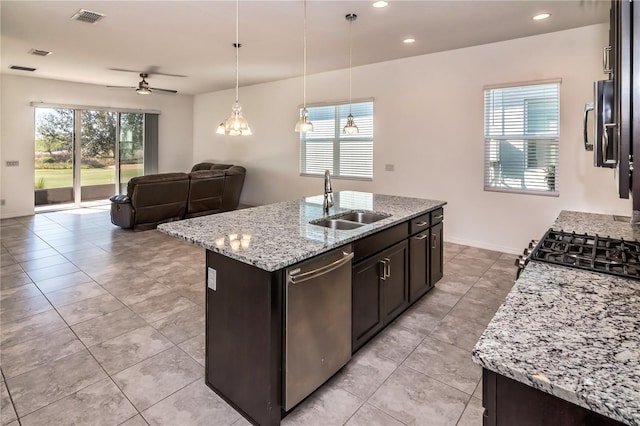 kitchen with dishwasher, a kitchen island with sink, sink, ceiling fan, and light stone countertops