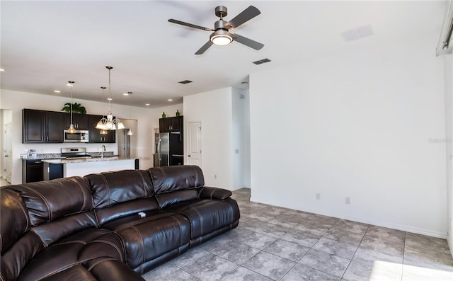 tiled living room featuring ceiling fan and sink