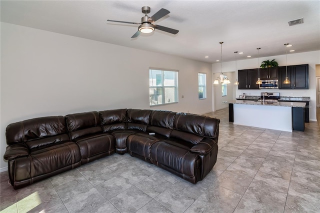 living room featuring ceiling fan with notable chandelier and sink