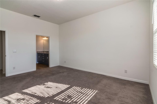 unfurnished bedroom with dark carpet and ensuite bath