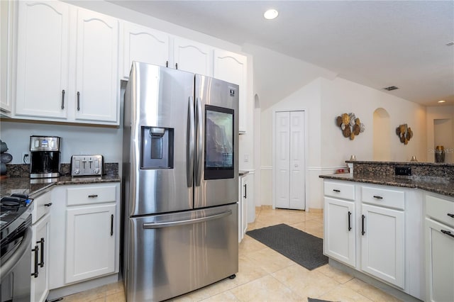 kitchen featuring white cabinets, appliances with stainless steel finishes, light tile patterned floors, and dark stone counters