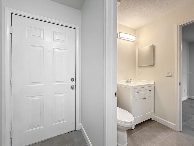 bathroom featuring tile patterned floors, vanity, toilet, and a textured ceiling