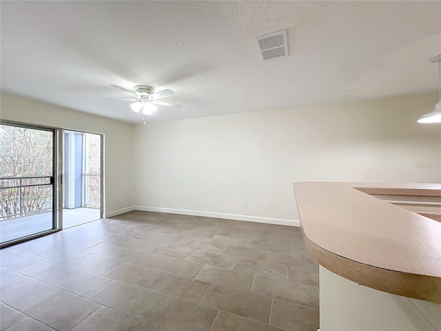 unfurnished room with ceiling fan and a textured ceiling