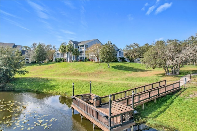 view of dock featuring a water view and a yard