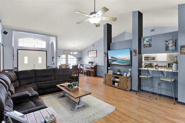 living room with high vaulted ceiling, ceiling fan with notable chandelier, and light hardwood / wood-style floors