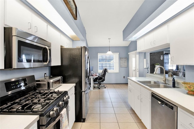 kitchen with sink, decorative light fixtures, light tile patterned floors, appliances with stainless steel finishes, and white cabinets