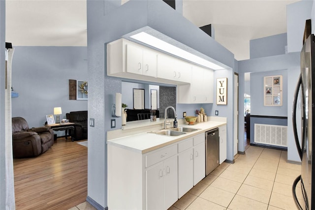 kitchen with white cabinetry, stainless steel dishwasher, sink, and light tile patterned floors