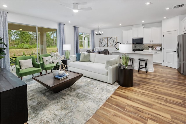 living room featuring light hardwood / wood-style flooring and ceiling fan with notable chandelier