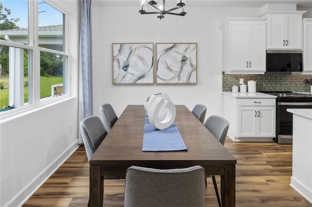 dining space with plenty of natural light, dark hardwood / wood-style floors, and an inviting chandelier