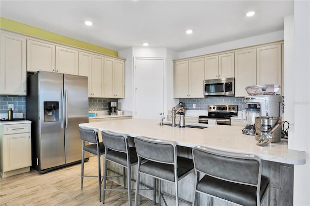 kitchen with appliances with stainless steel finishes, light wood-type flooring, cream cabinets, and sink