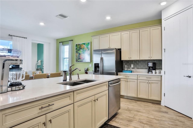 kitchen with cream cabinets, sink, light hardwood / wood-style floors, and appliances with stainless steel finishes