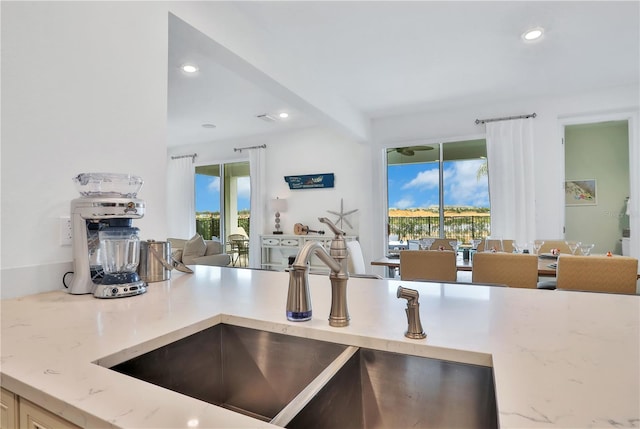 kitchen featuring light stone counters and sink