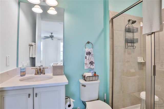 bathroom featuring vanity, toilet, ceiling fan, and a shower with shower door