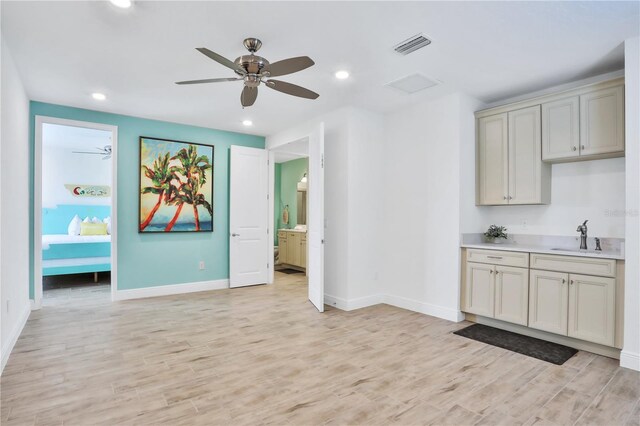 interior space featuring cream cabinets, ceiling fan, sink, and light wood-type flooring