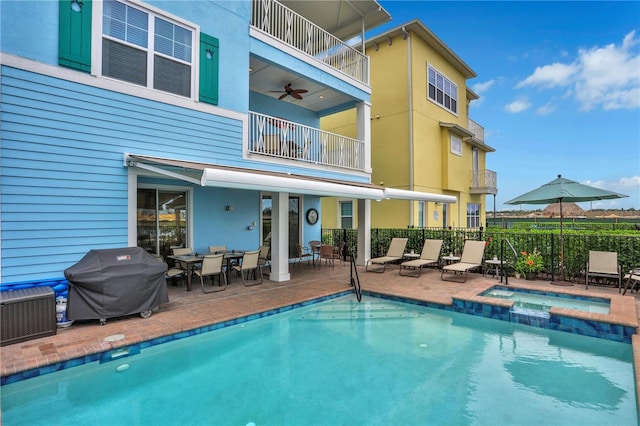 rear view of house with a swimming pool with hot tub, a patio area, and a balcony