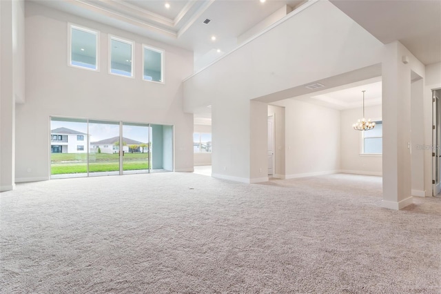 unfurnished living room with a chandelier, a high ceiling, and light colored carpet