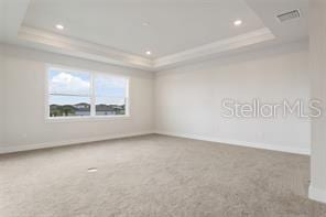 unfurnished room featuring carpet floors, a tray ceiling, and crown molding