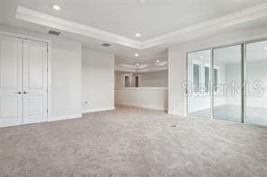 unfurnished bedroom with crown molding, a raised ceiling, light carpet, and two closets