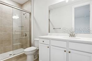 bathroom featuring an enclosed shower, vanity, and toilet