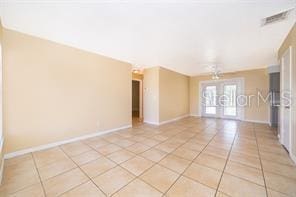 tiled empty room featuring french doors