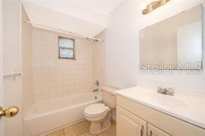 full bathroom featuring tile patterned flooring, vanity, tiled shower / bath combo, and toilet