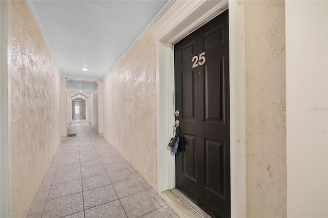 corridor with light tile patterned floors and ornamental molding