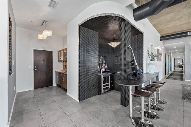 interior space featuring pendant lighting, wine cooler, and an inviting chandelier