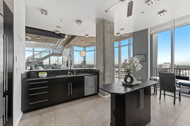 kitchen featuring ceiling fan, sink, stainless steel appliances, a kitchen island, and light tile patterned floors