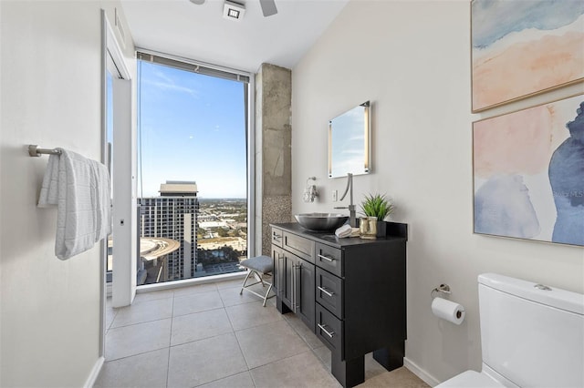 bathroom featuring tile patterned flooring, vanity, expansive windows, and toilet