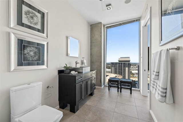 bathroom featuring tile patterned flooring, vanity, toilet, and a wall of windows