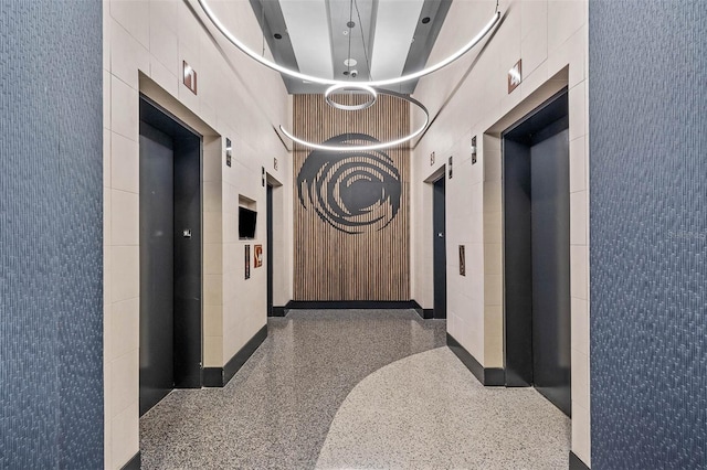 hallway featuring elevator and a high ceiling