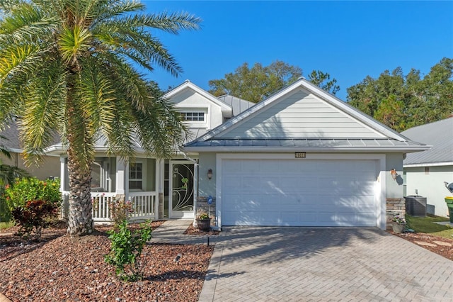 view of front of property featuring central AC unit, a garage, and covered porch