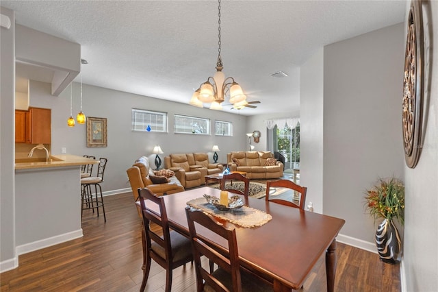 dining space with a textured ceiling, dark hardwood / wood-style flooring, and a notable chandelier