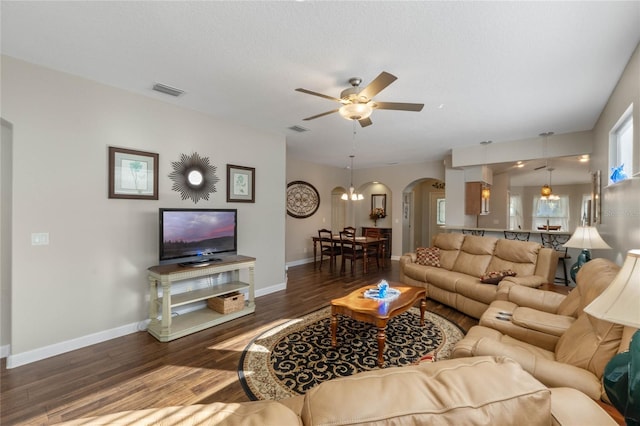 living room with dark wood-type flooring and ceiling fan with notable chandelier